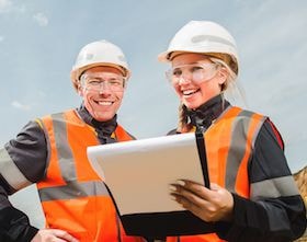 Workers in PPE reviewing safety documentation on site
